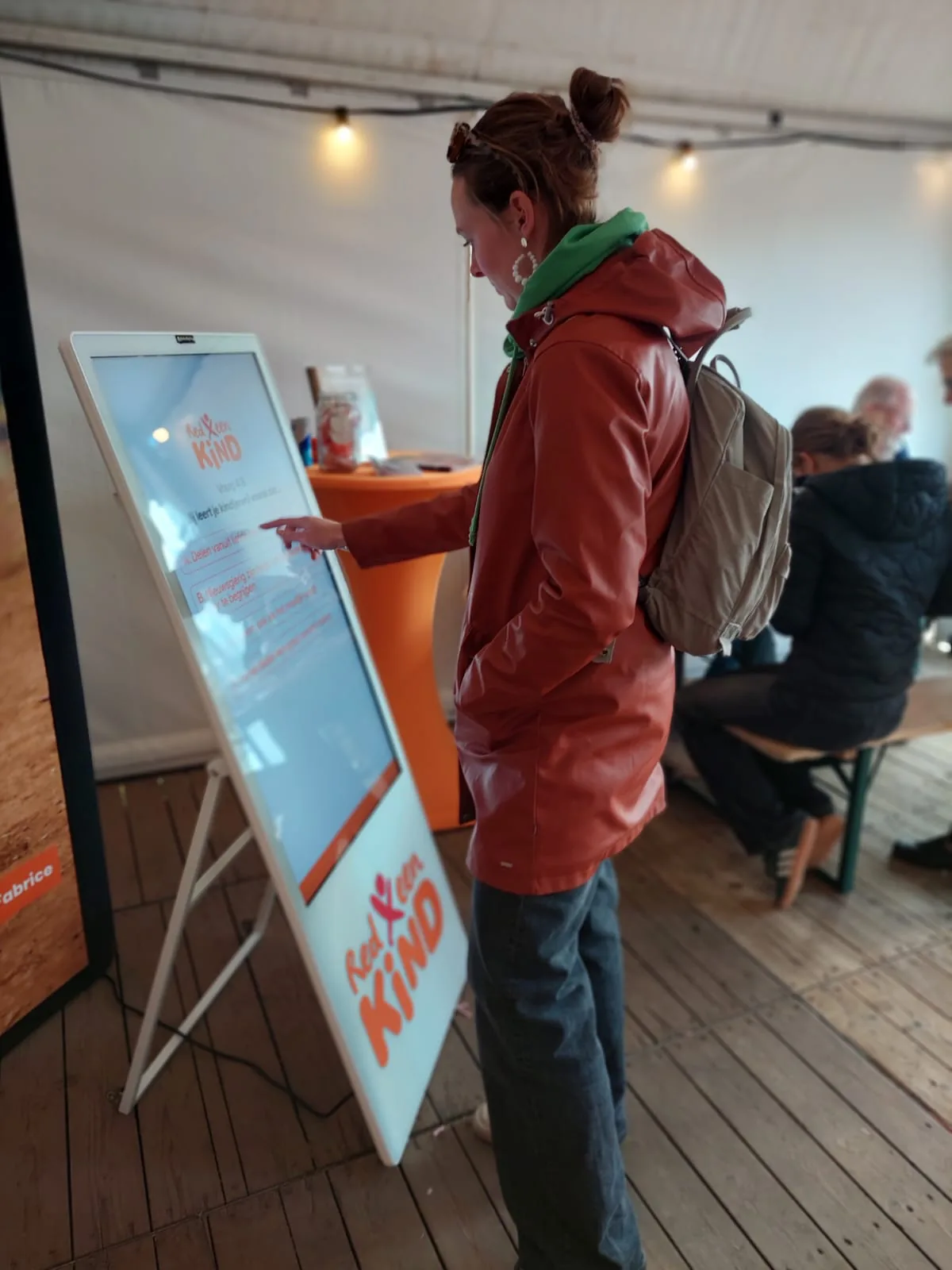 Bezoeker speelt de ouderschapsquiz van Red een Kind op een mobiel touchscreen tijdens een evenement